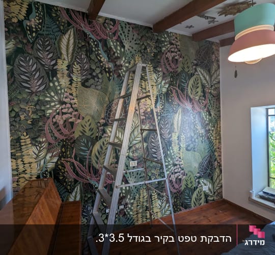 הדבקת טפט מעוצב בדוגמת צמחייה טרופית על קיר בחדר